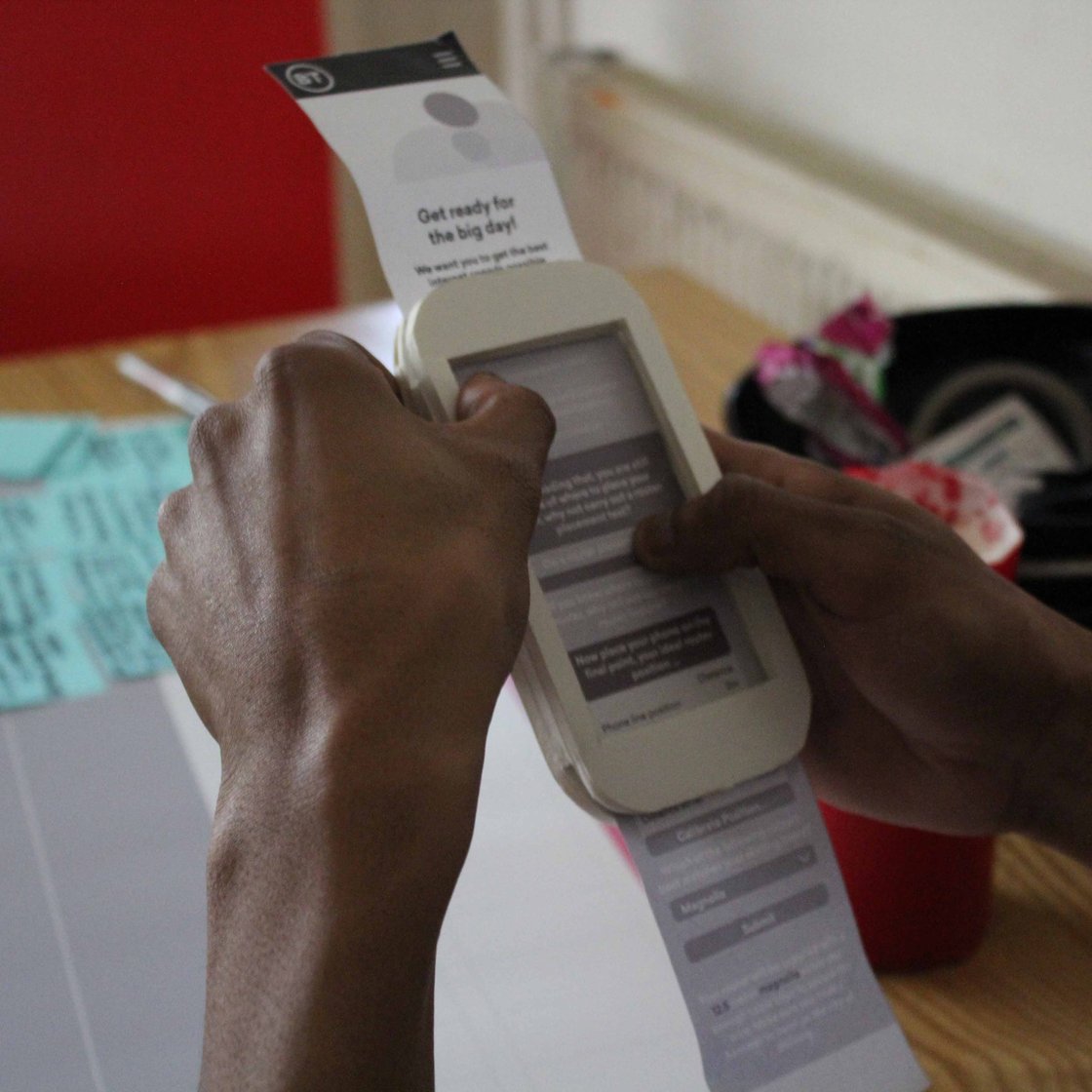 A customer research session featuring a Sacrificial Concept of a mobile app printed on paper and fed through a cardboard phone. 